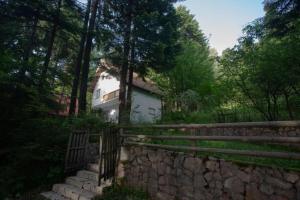 ein Haus hinter einer Steinmauer und einem Zaun in der Unterkunft Maison du Bonheur in Sarajevo