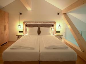 a bedroom with a large white bed with two pillows at Hotel Bütgenbacher Hof in Butgenbach