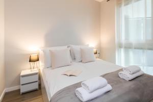 a bedroom with a white bed with towels on it at Flatbook Apartamenty - Jantar Resort in Jantar