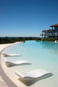 a swimming pool with white chairs in the water at Garda Lake Luxury Life in Padenghe sul Garda