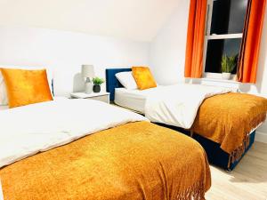 two beds in a room with orange curtains at Dover luxury apartments, near Ferry in Dover