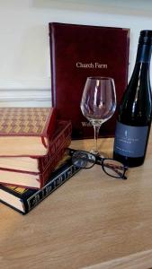 ein Stapel Bücher neben einer Flasche Wein und einem Glas in der Unterkunft Church Farm Guest House in Horsford