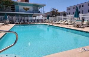 a large blue swimming pool with chairs and umbrellas at Eden Roc Apartments in Ocean City