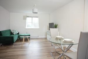 uma sala de estar com uma mesa de vidro e um sofá verde em Stylish Pride Park DERBY Apartment - Free WIFI, Parking em Derby