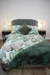 a bed with a green and white comforter and pillows at Stylish Pride Park DERBY Apartment - Free WIFI, Parking in Derby