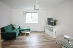 a living room with a green couch and a table at Stylish Pride Park DERBY Apartment - Free Netflix, WIFI, Parking in Derby