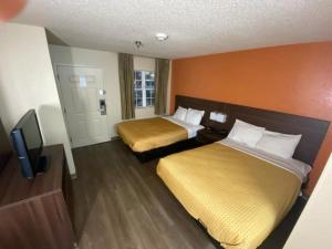a hotel room with two beds and a flat screen tv at Suburban Studios Winston-Salem near Hanes Mall in Winston-Salem