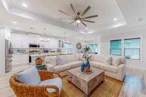 sala de estar con muebles blancos y ventilador de techo en Driftwood Dreams, en Panama City Beach