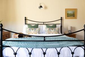 a bedroom with a bed with a black frame and pillows at Yew Tree Cottage in Ayton