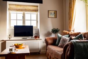 a living room with a couch and a flat screen tv at Yew Tree Cottage in Ayton