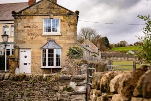 an old stone house with a stone wall at Yew Tree Cottage in Ayton