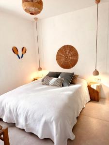 a bedroom with a large white bed and two pendant lights at Can Yuca I in Santanyi