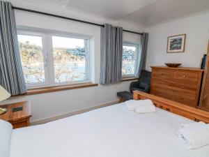 a bedroom with a bed and a chair and windows at Leeward in Dartmouth