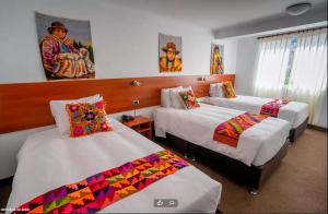 a bedroom with three beds with colorful quilts at Hotel Romero Cusco in Cusco