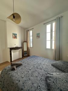 una camera da letto con un letto con una coperta blu e due finestre di Le Mourillonnais a Tolone