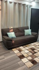- un canapé brun dans le salon avec des rideaux dans l'établissement NBA PLUSH APARTMENT - NSROMA, à Accra