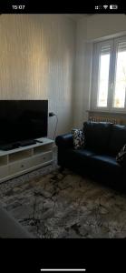 ein Wohnzimmer mit einem schwarzen Sofa und einem Flachbild-TV in der Unterkunft YellowHouse in Gallarate