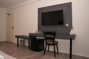 a desk with a chair and a television on a wall at GN Hotel Furpach in Neunkirchen