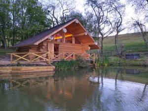 a log cabin sitting on top of a body of water at Log Cabin/Hot Tub on Private Lake Jurassic Coast in Bridport