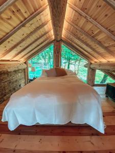 a bed in a room with a large window at Log Cabin/Hot Tub on Private Lake Jurassic Coast in Bridport