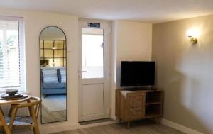 a living room with a tv and a door with a mirror at The Cwtch in Ludlow