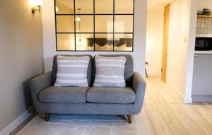 a gray couch with two white pillows in a living room at The Cwtch in Ludlow