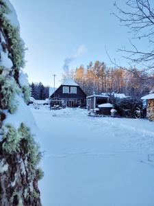 una casa con nieve en el suelo delante de ella en Trainiškio pirkia en Ginučiai