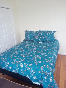 a bed with a blue bedspread with flowers on it at One bedroom with free parking in Schenectady