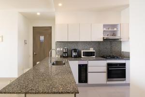 a kitchen with white cabinets and a granite counter top at 41st Fl Beach Condo in Bocagrande in Cartagena de Indias