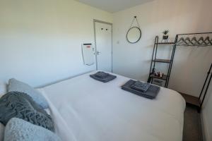 ein Schlafzimmer mit einem weißen Bett mit zwei Handtüchern darauf in der Unterkunft Find peace in a chalet by the beach in Kessingland