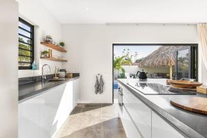 a kitchen with white counters and a large window at Villa Mambo Royale in Willemstad