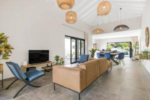 a living room with a couch and chairs and a tv at Villa Mambo Royale in Willemstad