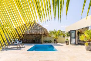 a resort with a swimming pool and a straw hut at Villa Mambo Royale in Willemstad
