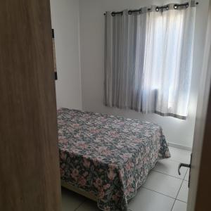 - une petite chambre avec un lit et une couverture fleurie dans l'établissement APARTAMENTO CONDOMÍNIO SUN WAY, à Ubatuba