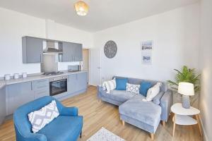 uma sala de estar com duas cadeiras azuis e uma cozinha em Stunning Seaview 2 Bedroom Apartment em Redcar