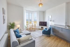 uma sala de estar com um sofá e uma mesa com cadeiras em Stunning Seaview 2 Bedroom Apartment em Redcar