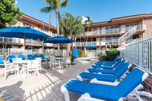 a patio with blue and white chairs and tables and umbrellas at Canada House Beach Club Resort in Pompano Beach