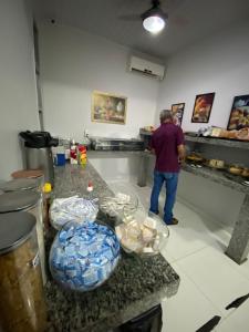 un hombre de pie en una cocina preparando comida en Hotel dos viajantes, en Sorriso