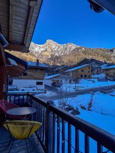 a balcony with a table and chairs and snow covered mountains at Chalet La Savoyarde in Peisey-Nancroix