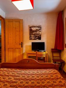 a bedroom with a bed and a desk with a television at Chalet La Savoyarde in Peisey-Nancroix