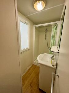 a white bathroom with a sink and a window at Camper Village in Santo Stefano al Mare