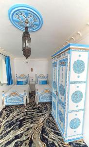una camera con 2 letti bianchi e blu e un lampadario a braccio di Dar La Aicha a Chefchaouen