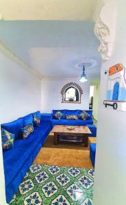 舍夫沙萬的住宿－Dar La Aicha，客厅配有一张蓝色的沙发,配有一张桌子