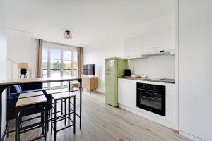 een keuken met witte kasten en een groene koelkast bij La Résidence Alpha Viroflay 302 - Duplex 2 chambres - 4 pers in Viroflay
