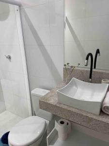 uma casa de banho branca com um lavatório e um WC em Flat Completo em Vila Velha