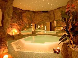a hot tub in a stone room with candles at Hotel Foestlerhof in Villa Ottone