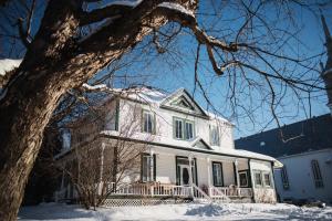 a white house with snow on the ground at Auberge Incroyable in Saint Adrien