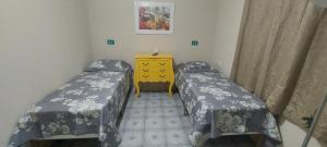 a small room with two beds and a yellow dresser at Pousada Palmeira in Viracopos