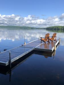 two chairs sitting on a dock on a lake at Chalet des bouleaux in Nominingue