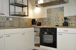 a kitchen with white cabinets and a black oven at L'Hirondelle - Charming flat - in Blotzheim